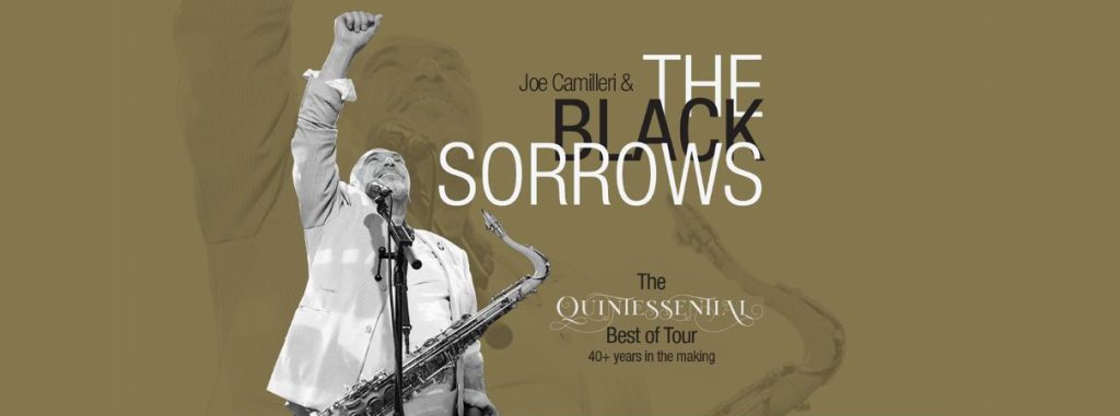 A man in a light blazer raises his fist while holding a saxophone and singing into a microphone. The text reads: Joe Camilleri & The Black Sorrows. The Quintessential Best of Tour. 40+ years in the making.