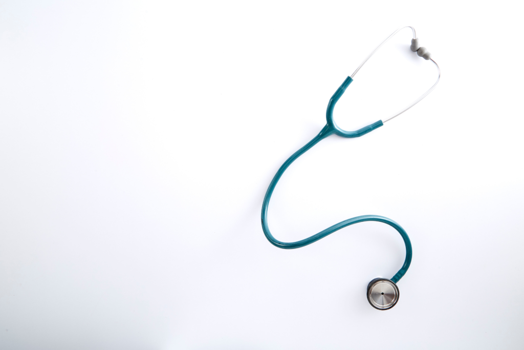 A teal stethoscope with silver earpieces and chest piece is placed on a white background, arranged in a loose, curved shape.